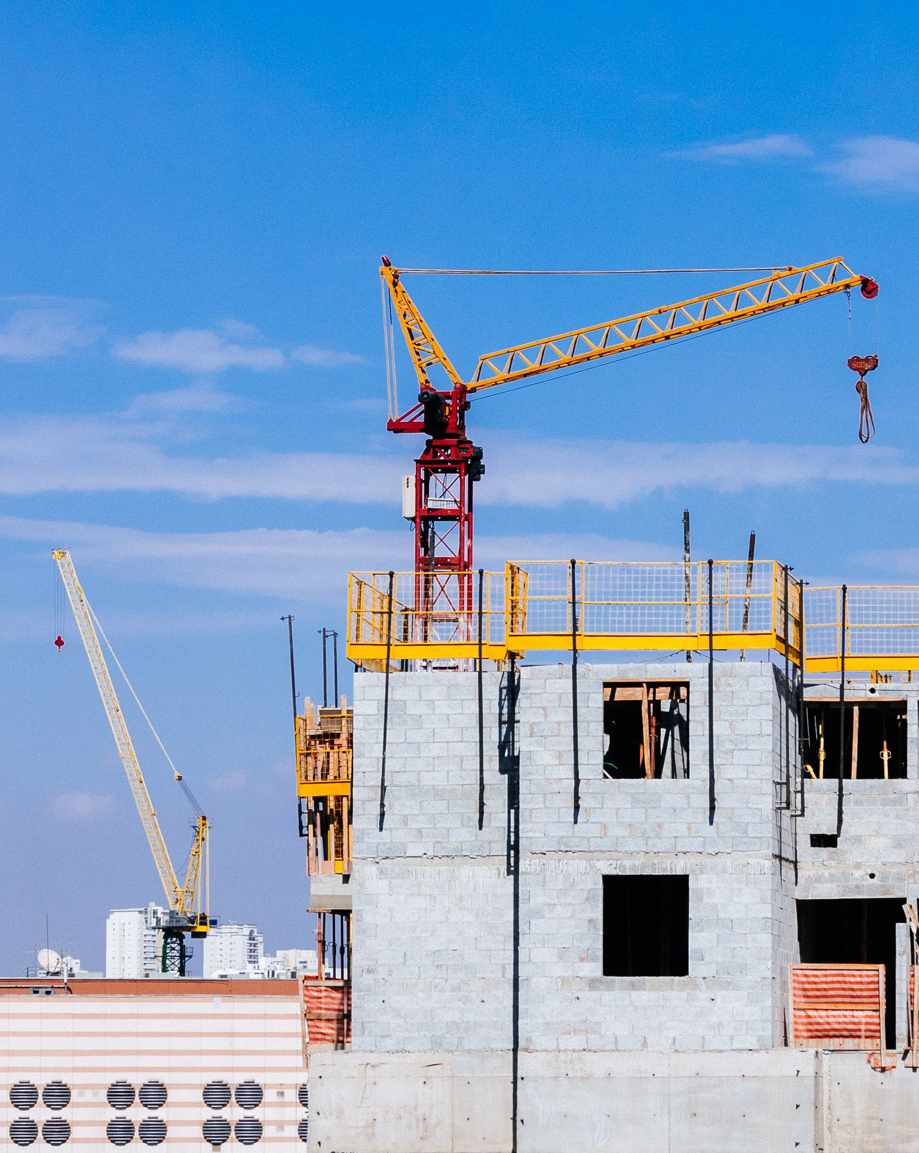 Tower cranes above a high-rise building under construction on a clear day
