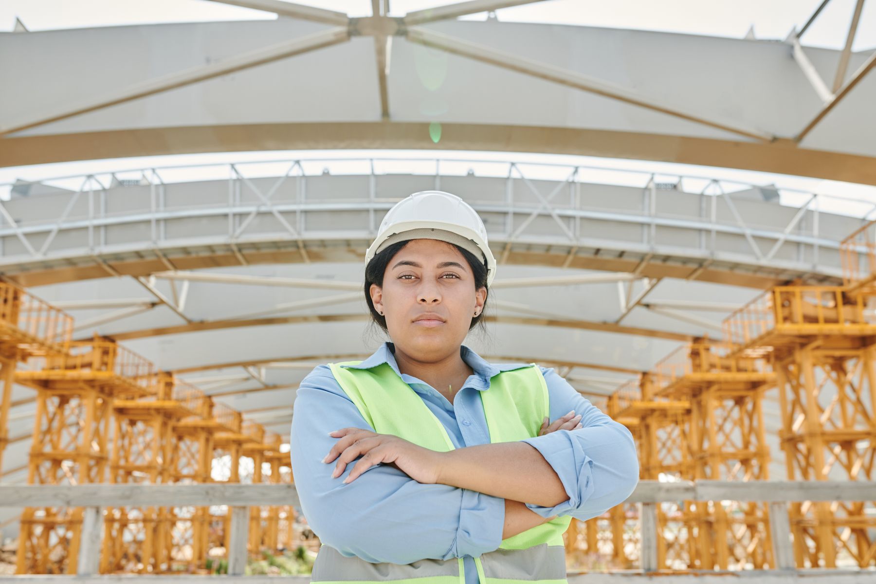 Engineer wearing a safety helmet and vest standing in front of a steel structure