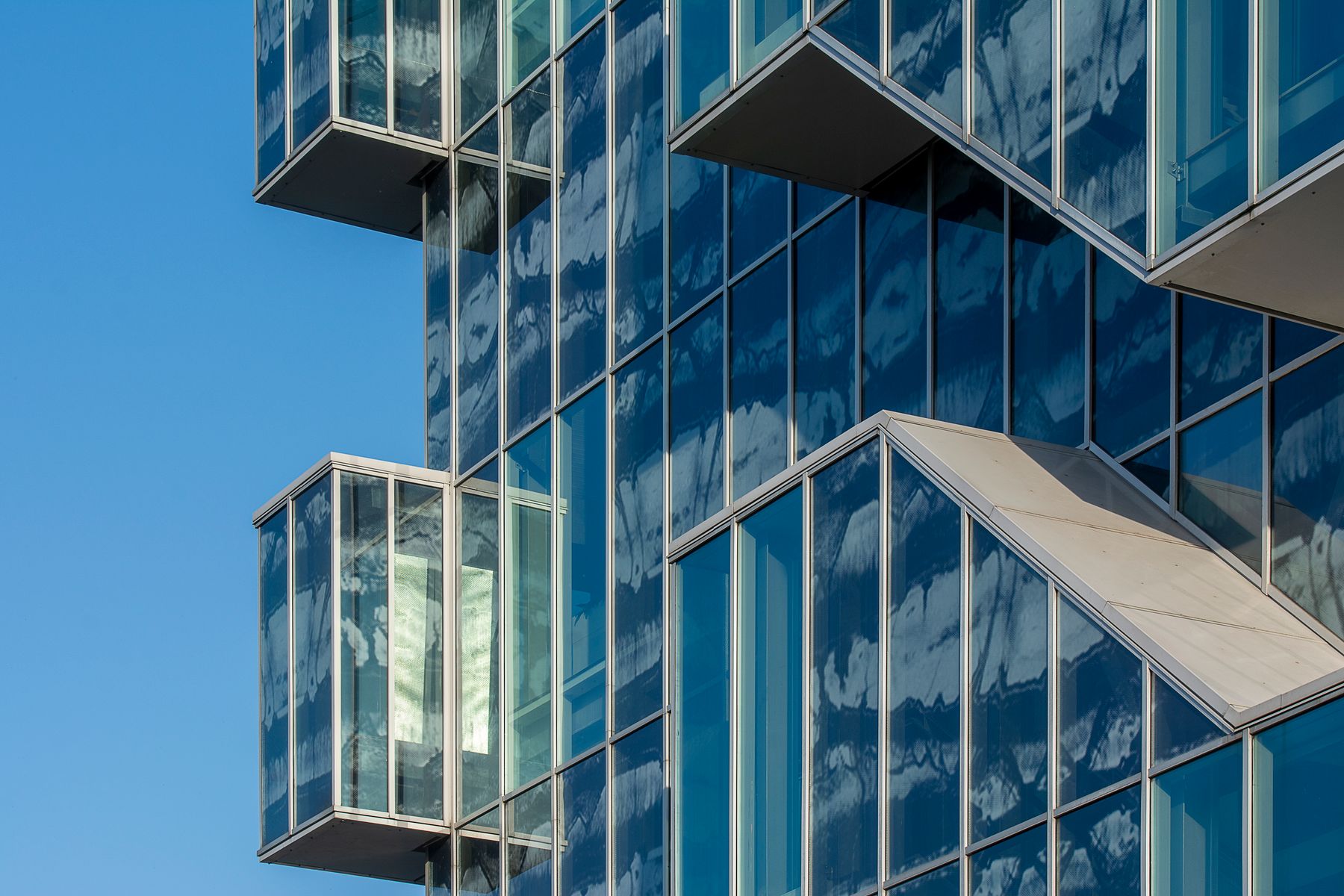 Glass façade with projecting window boxes reflecting the sky