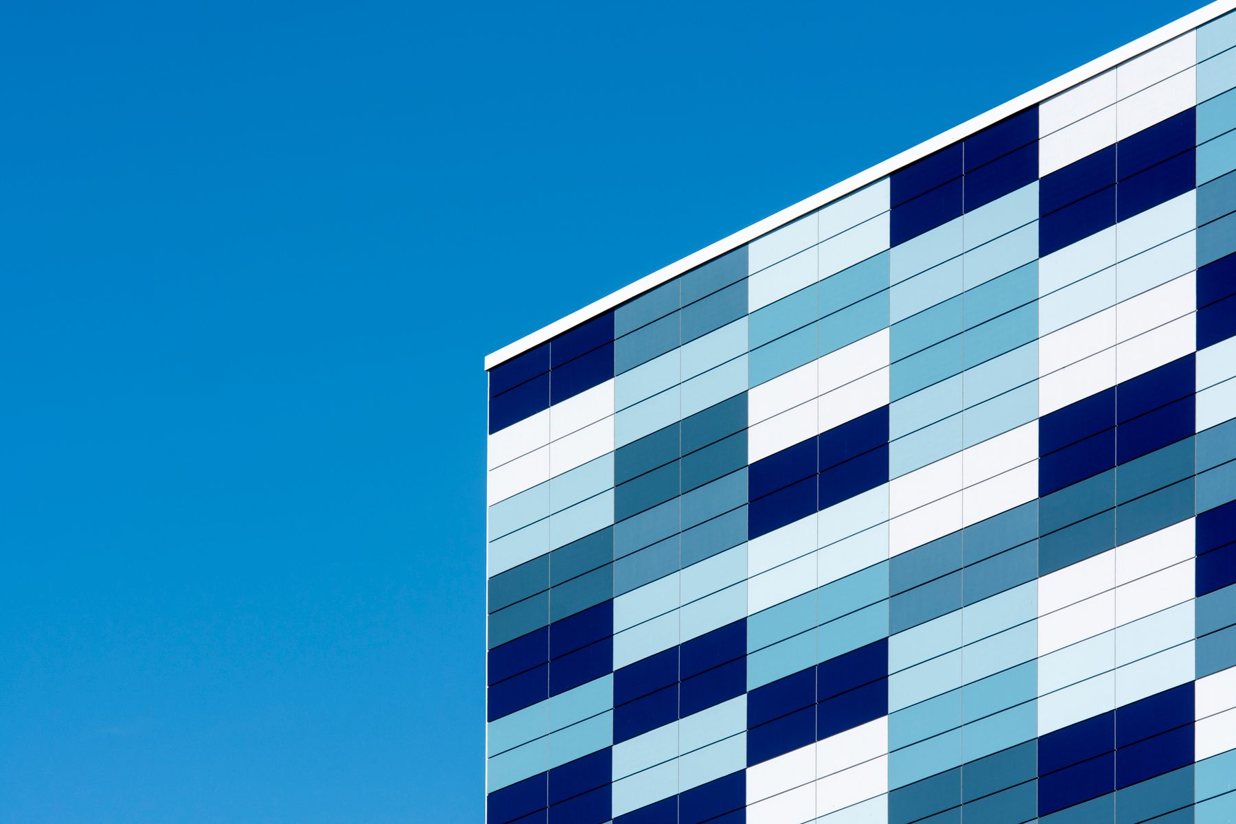 Modern building façade with blue and white glass panels against a clear sky