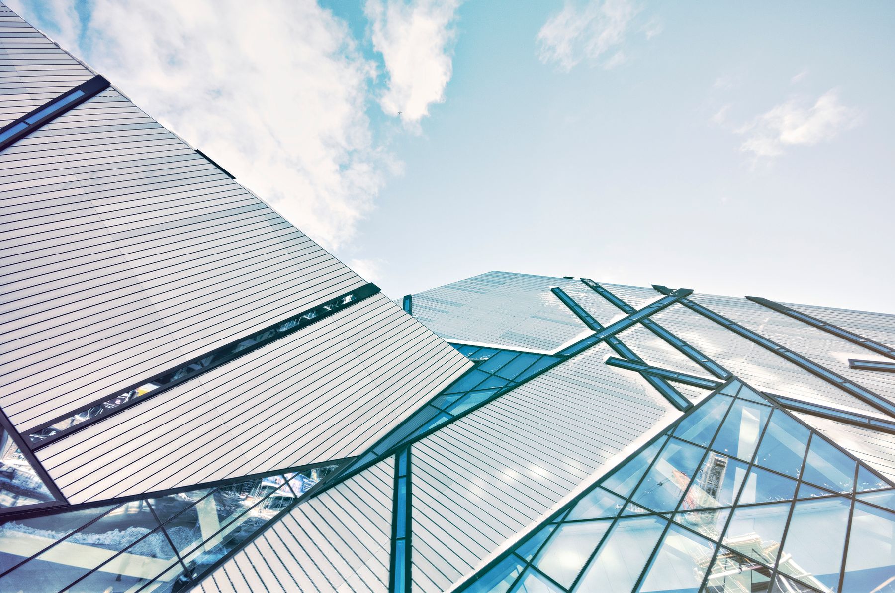Glass office tower seen from below against a blue sky