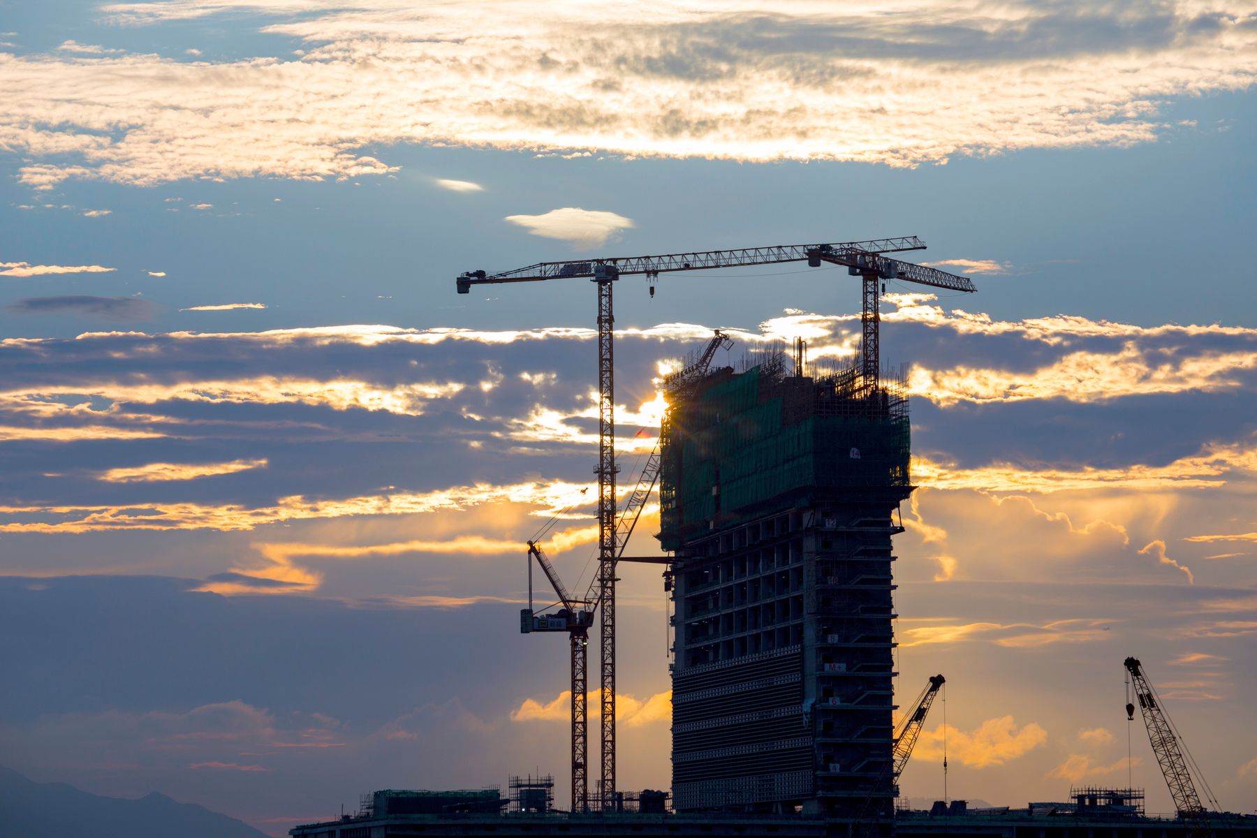 Construction site with a crane silhouetted against a sunset sky