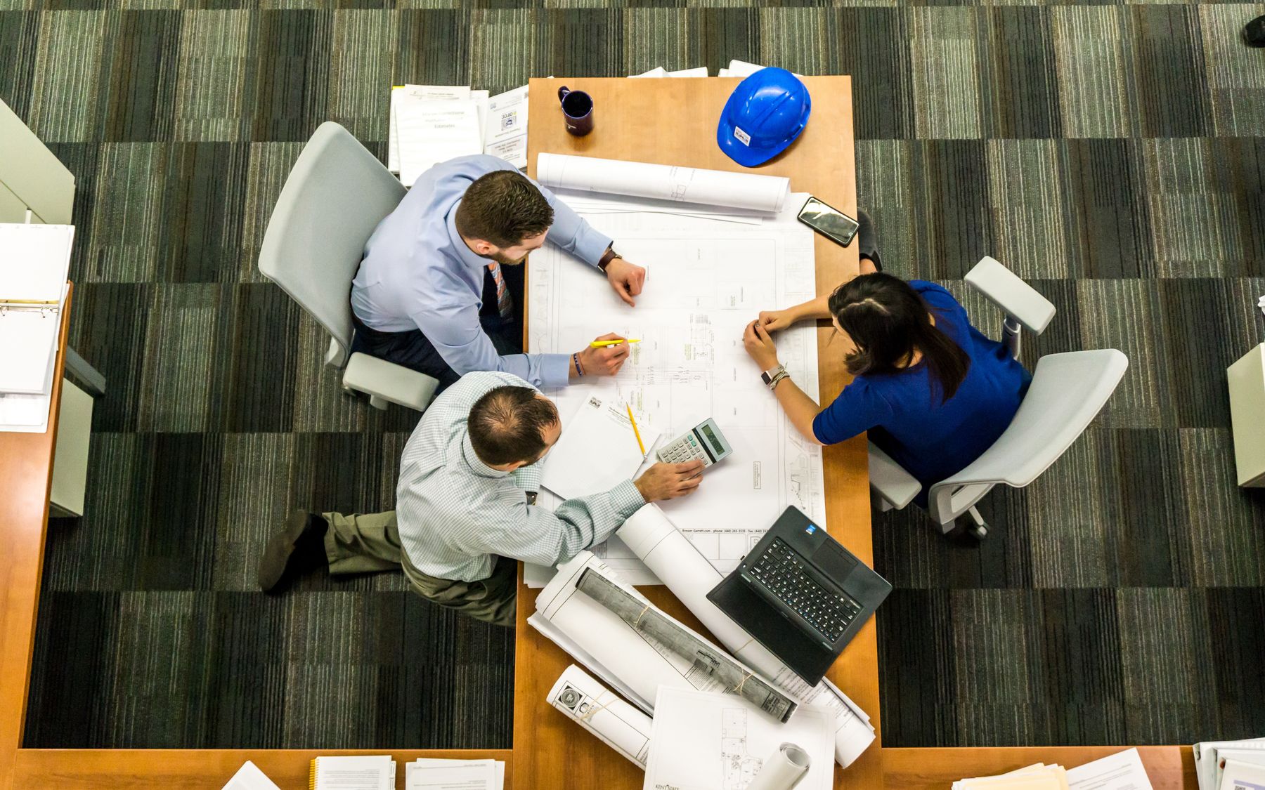 Project team reviewing drawings and plans around a table, seen from above