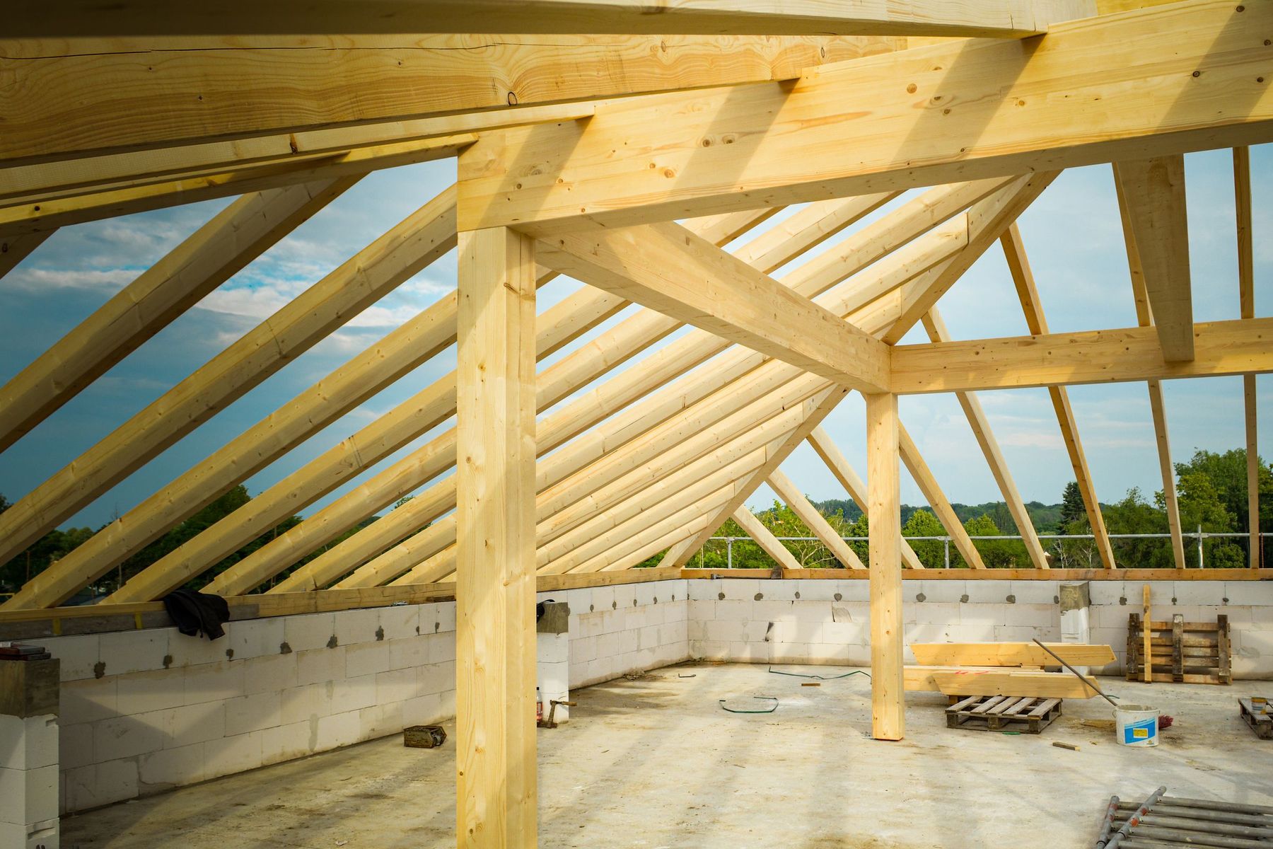 Timber post-and-beam roof structure rising above the walls of a building under construction