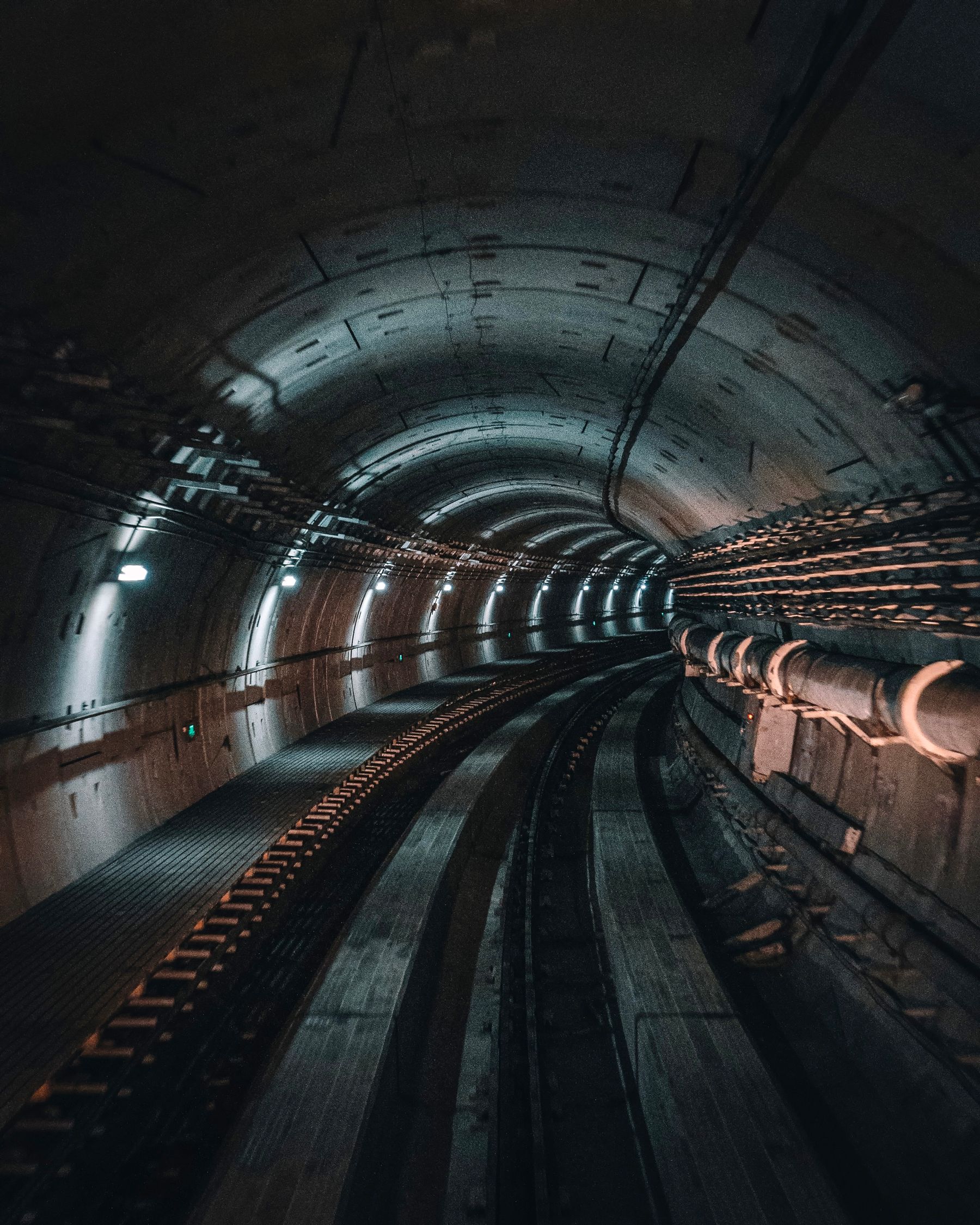 Underground tunnel with utility pipes and cables running along the wall